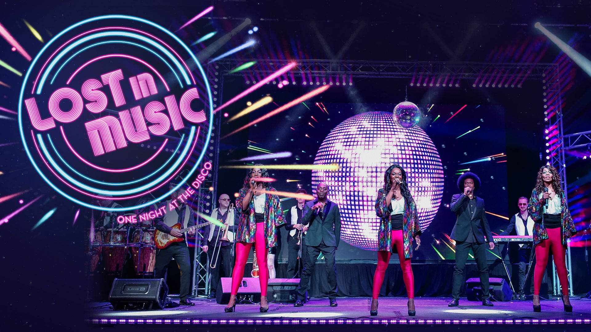 Large disco ball sits behind group male and female singers holding microphones and looking straight ahead